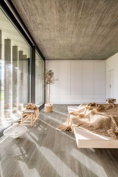 quarto de uma casa moderna com janela de vidro grande e uma cama moderna e piso vinilico marrom